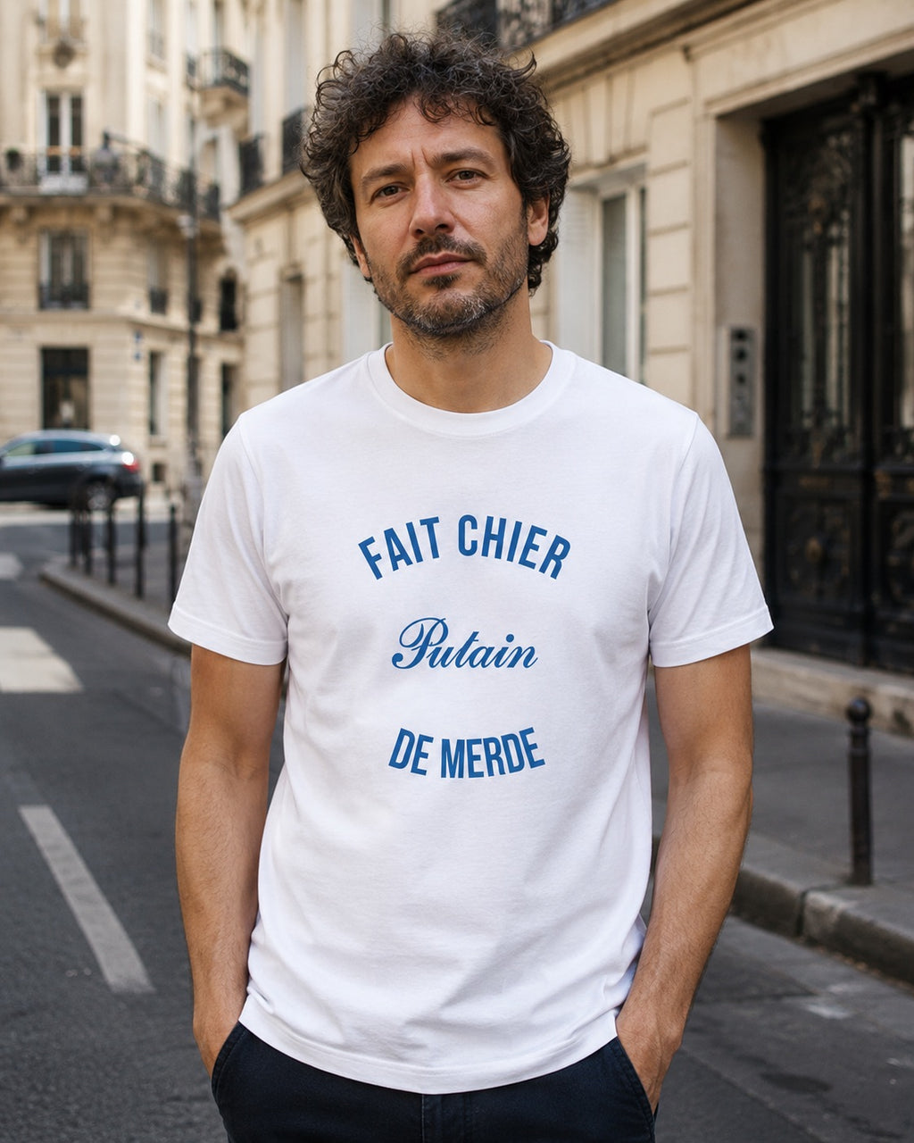 Man wearing a white t-shirt with blue text on a city street.