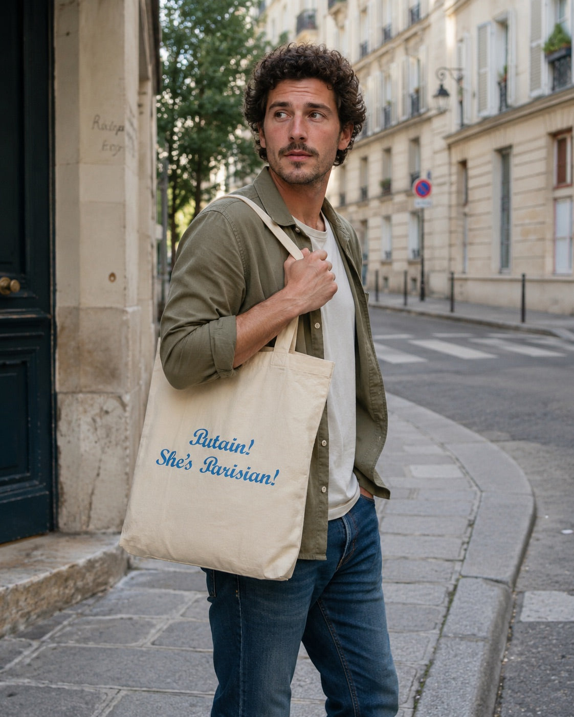 Man holding a tote bag with text on a city street